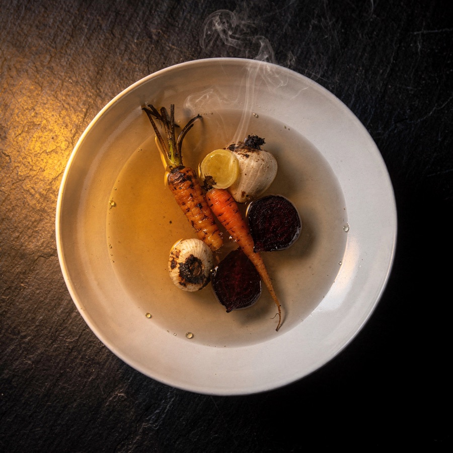 Mineral broth with charred roots and a mark of smoke, ember-lit.