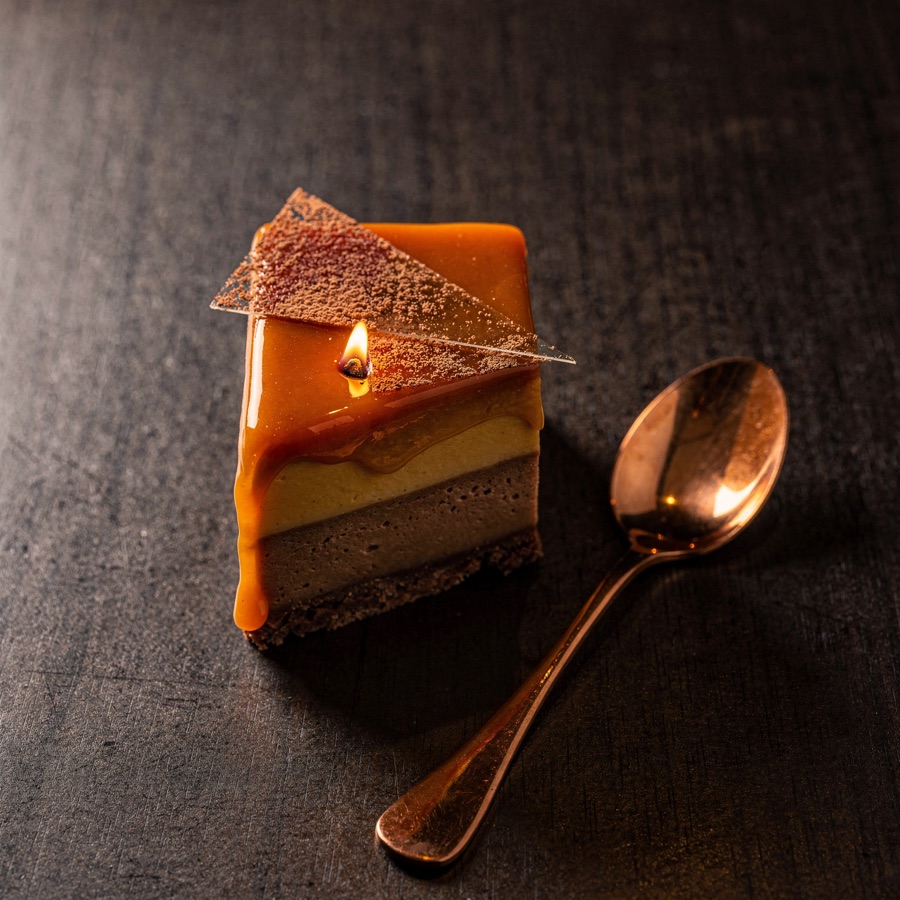 Caramel and cacao dessert with a cooling dusting, copper spoon beside.